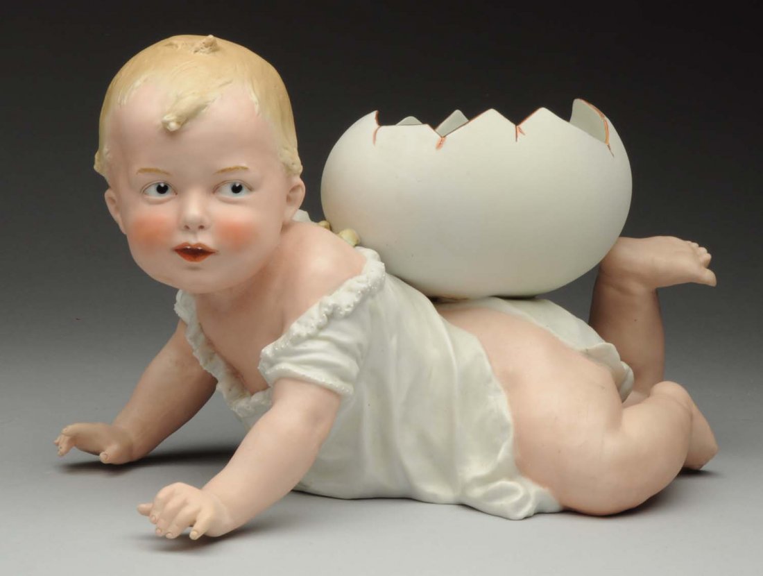 Exceptional Heubach Piano Baby.: Crawling baby with molded shift and egg container on his back, lovely face (faint 1” firing line on forehead). Gebr. Heubach incised on base. Wonderful large baby! Condition (Very Good). Size 12" x