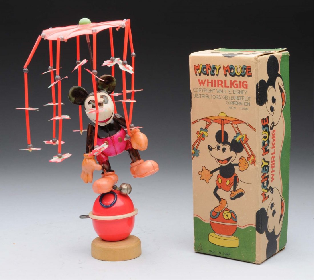 Japanese Walt Disney Mickey Mouse Whirligig Toy.: This celluloid wind - up toy includes scarce colorful original box, depicts Mickey on celluloid ball with wood base. On top of Mickey's head spins a celluloid carousal. Carousal is missing two small f