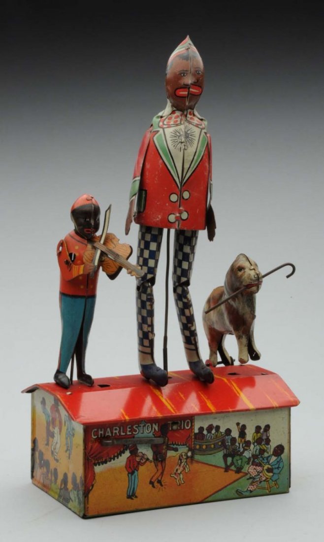 Marx Tin Litho Wind-Up Charleston Trio Toy.: Depicts African American man dancing while the man to the left plays the violin, and the dog to the left jumps up and down holding cane. Includes original arms. Some scratching and edge wear. Conditio