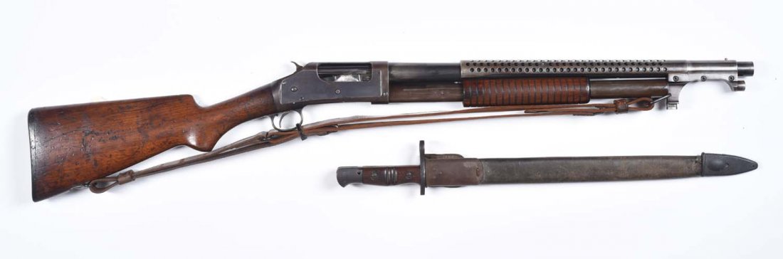 Winchester 1897 Trench Pump Shotgun. **: Serial No. 448176. 12 gauge. Manufactured in 1909. Barrel length: 20 - 3/4". Choke dimension: cylinder. Remington with bayonet and sling made up gun. Barrel and frame are blue to patina, has scrapes. 
