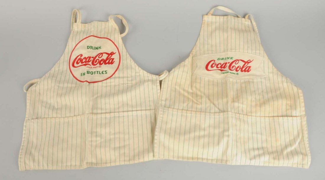 Lot of 2: Earlier Coca - Cola Aprons.: One apron has moderate staining and the other is clean and bright. Condition (Very Good Plus). Size Largest : 28 -1/2" L.