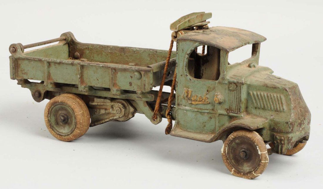 Cast Iron Arcade Mack Dump Truck.: White rubber tires, dual rear tires. Tires do have some alligatoring and cracking. Embossed "Mack" on both sides of front door. Includes original plunger. Back tail gate is intact. Missing driver. Com