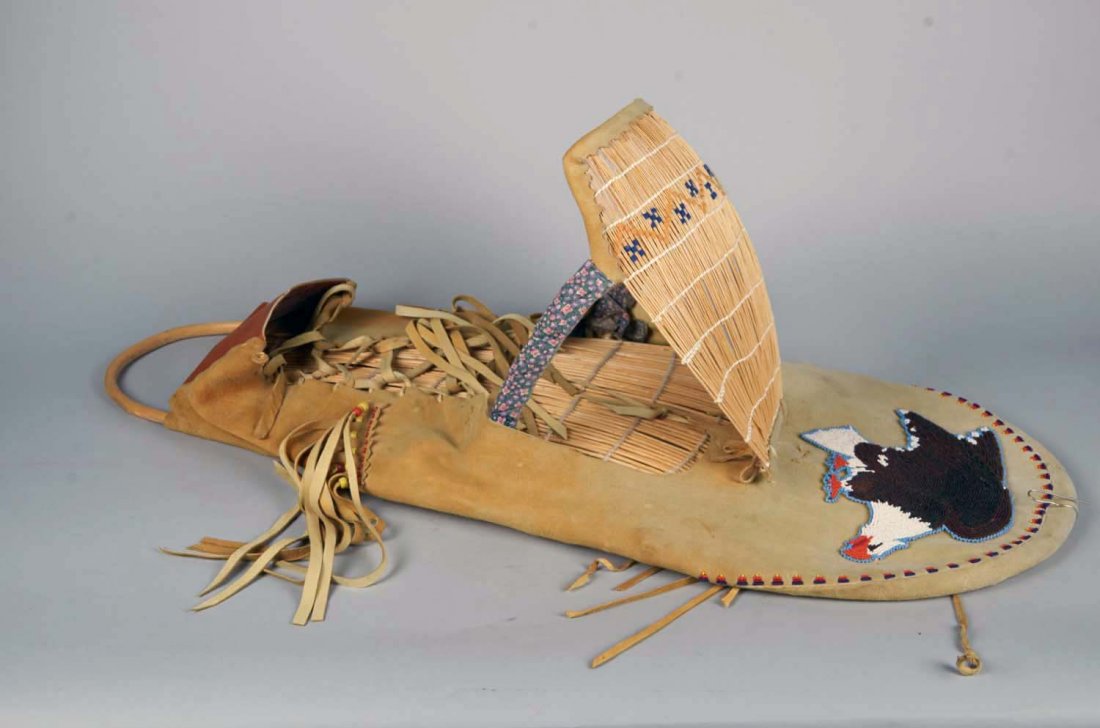 American Indian Cradleboard Papoose Carrier: Bald eagle beadwork on front and fringe suede leather throughout, built over flexible wood frame. Condition (Very good). Size 37" x 12" x 15"