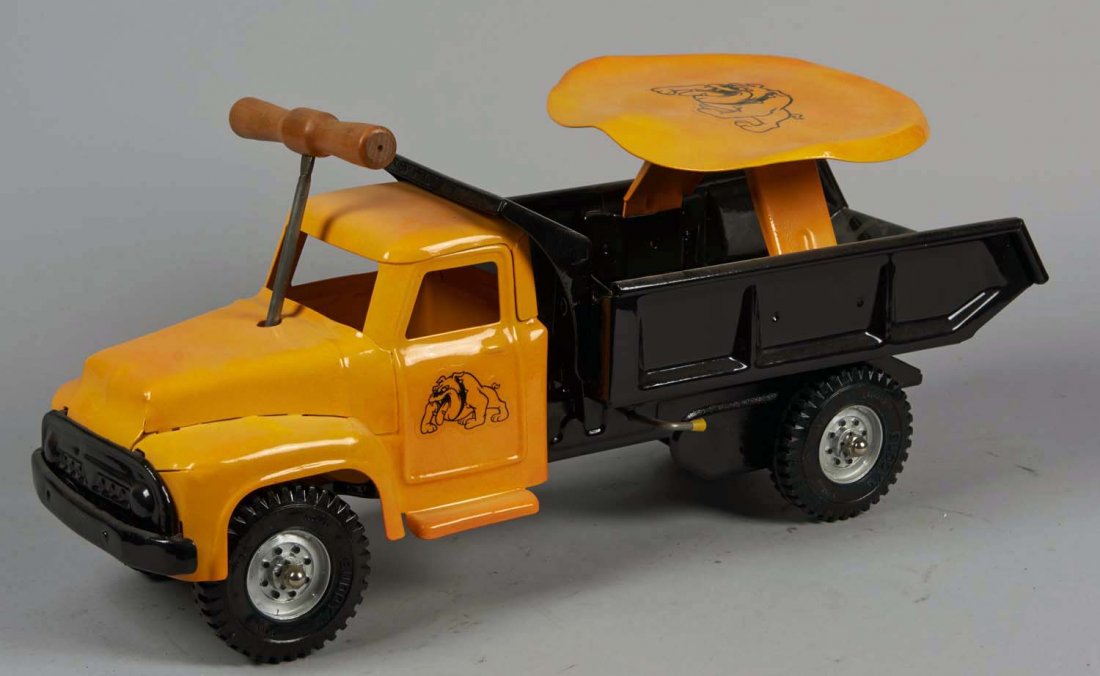 Pressed Steel Buddy L Hydraulic Dump Truck: Pull-N-Ride truck with yellow seat and tractor, black dump bed, bulldog decals, and Buddy L plastic tires. Condition (Excellent). Size 20" L.