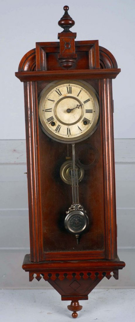 Antique Waterbury Walnut Pendulum Wall Clock: With glass door and pendulum. Opens on left side with Roman numeral dial face. Has partial original paper Waterbury Clock Co. decal on back. Includes key. Condition (Very good). Size 10" x 4-1/2" x 31