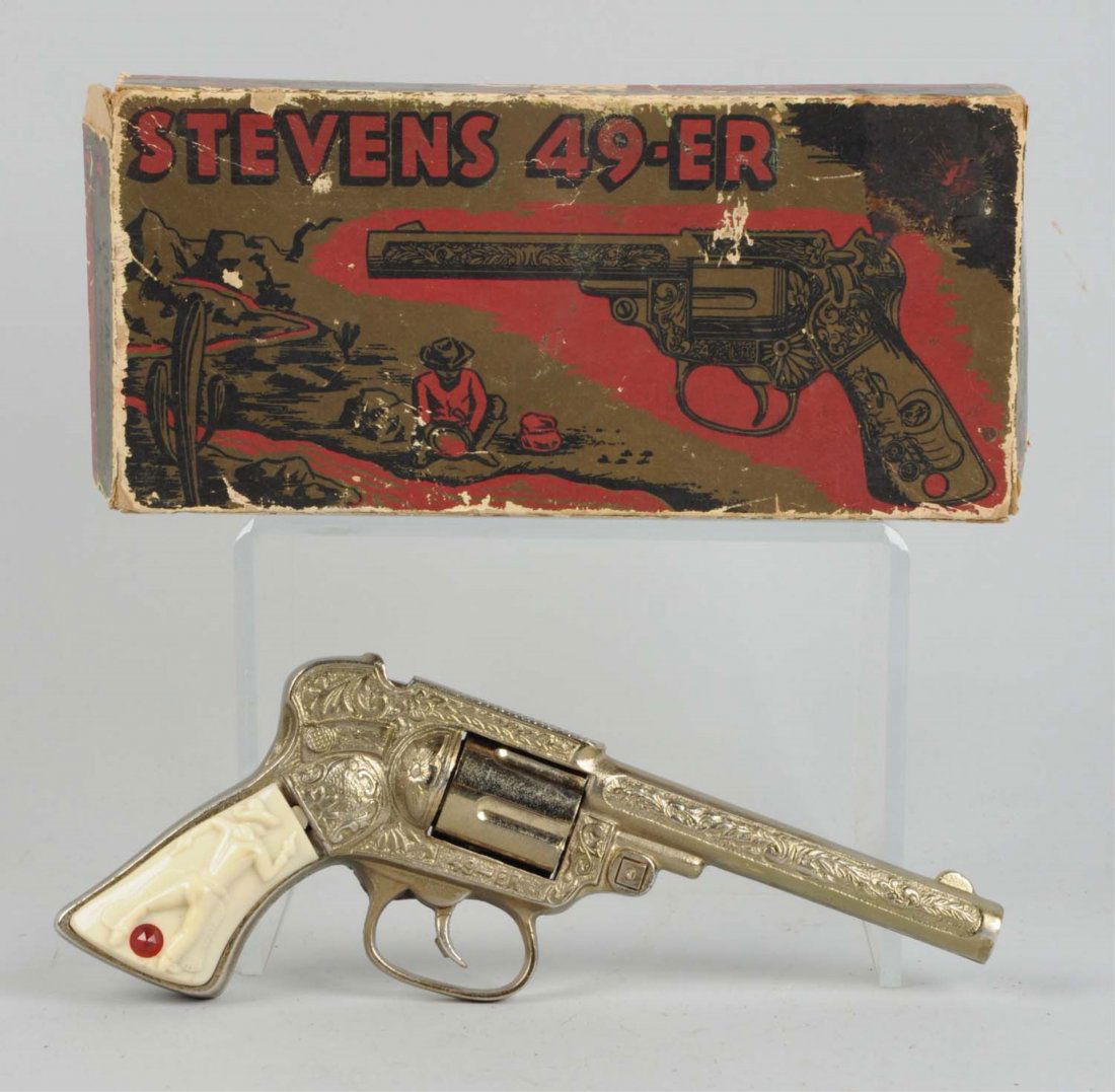 Stevens Cast Iron 49-er Revolving Cyl. Cap Gun.: Includes original box, gun has "49-er" on both sides underneath cylinder. Has embossed pioneer wagon and cowboy on grips. Somewhat used. Box has some splitting and some paper loss. Condition (Very Goo