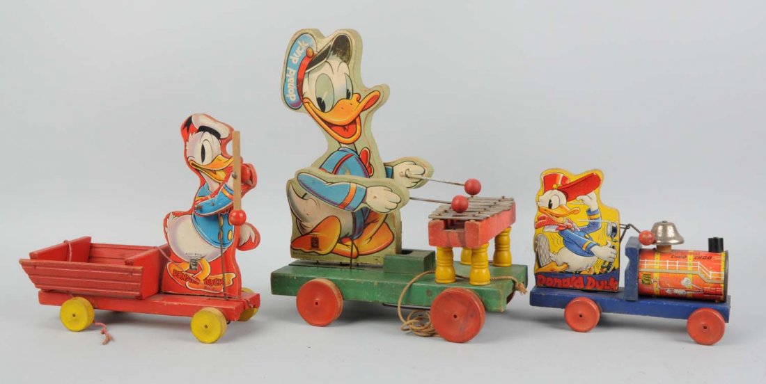 Lot of 3: Fisher-Price Disney Donald Toys.: Includes xylophone player, cart toy, and one choo - choo. The scarcer choo - choo No. 450 with Donald's red hat. Some oxidation to keys on xylophone. Some edge wear and paper creasing. Condition (Very