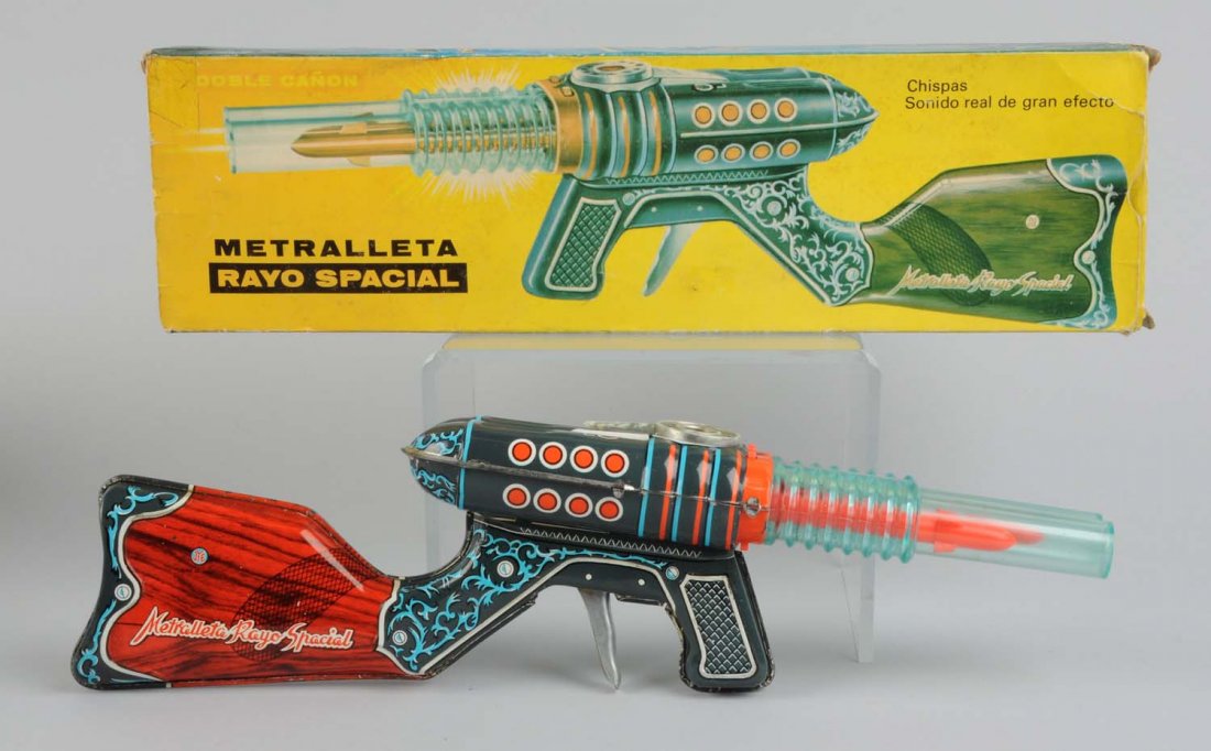Tin & Plastic Friction Double Barrel Gun With Box: Made in Spain. The gun has some minor scratches, mainly towards the bottom, otherwise the tin section is very nice and colorful. Gun reads "Metralleta Rayo Spacial" on both sides of tin stock. The bar