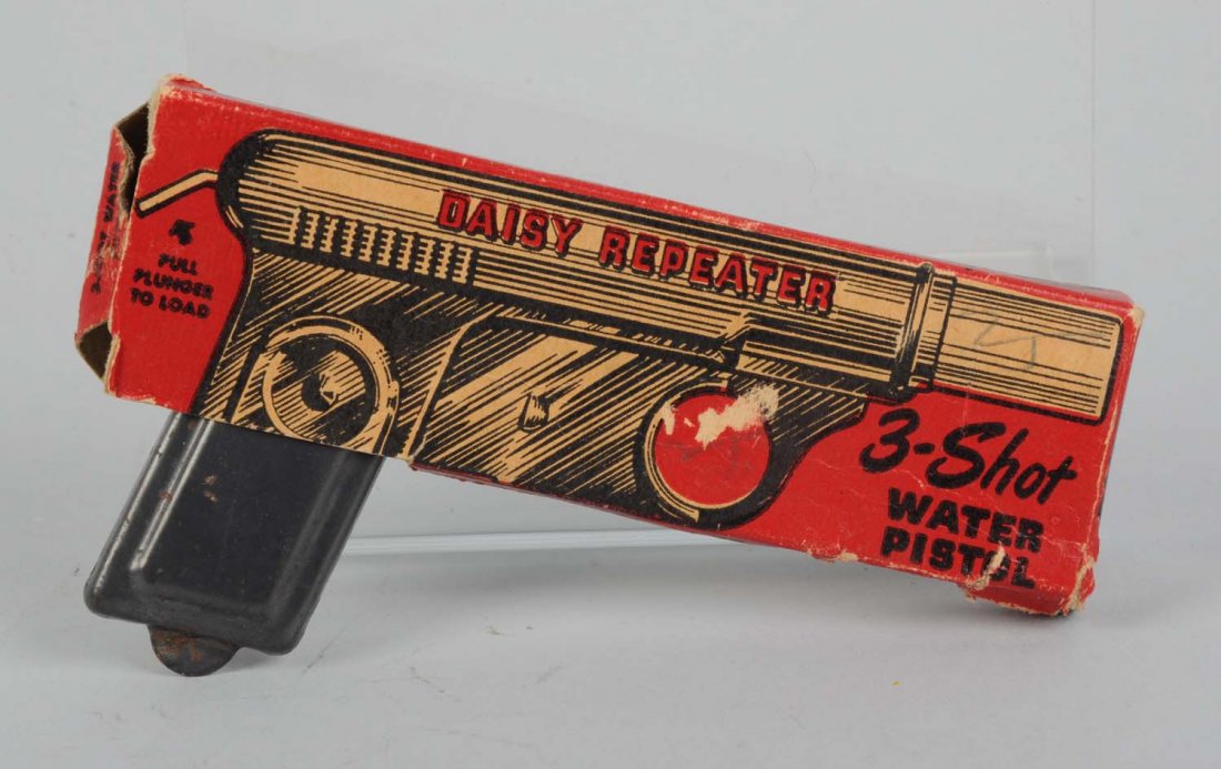 Tin Three-Shot Water Pistol In Box.: Made by Daisy Manufacturing Co. in the USA. Pistol has many spots of oxidation throughout. Includes the original box that has some creasing, paper pulls, and tears. Condition (Good - Very Good). Size
