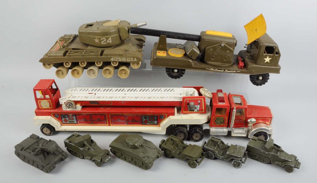 Lot Of 9: Various Vehicles.: Lot includes a plastic tractor trailer with a fire truck with ladders, a plastic military tank, pressed steel truck with a cannon on its flatbed, and two metal tanks and four various Jeeps and trucks.