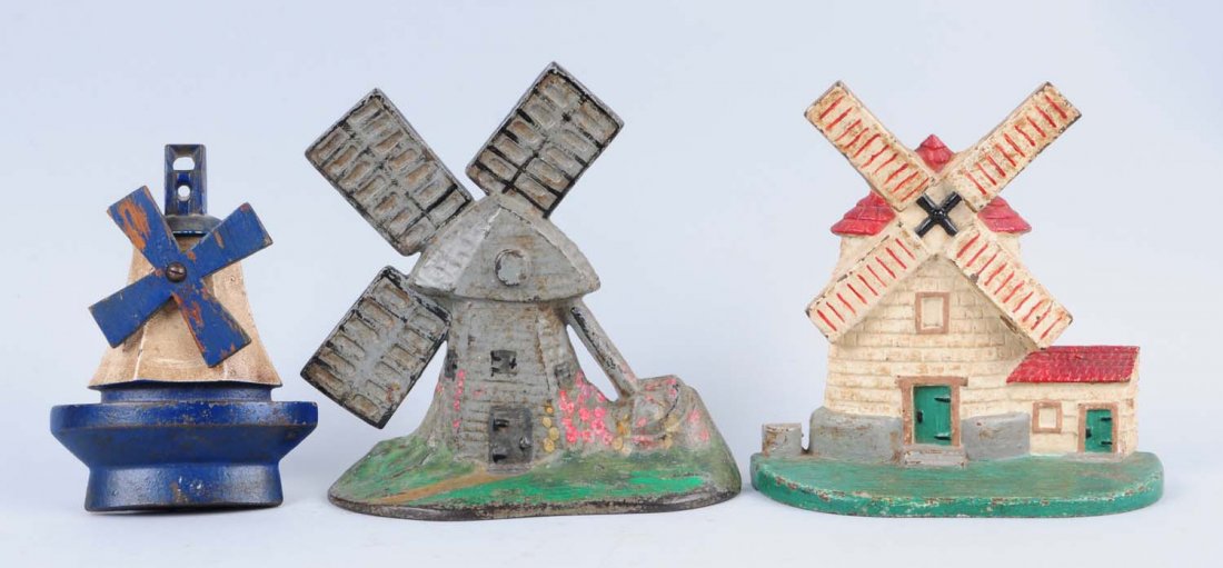 Lot Of 3: Cast Iron Windmill Doorstops.: Includes – two windmill doorstops, and windmill sconce, missing lamp. Condition (Very Good). Size Largest: 7 - 3/8" T.