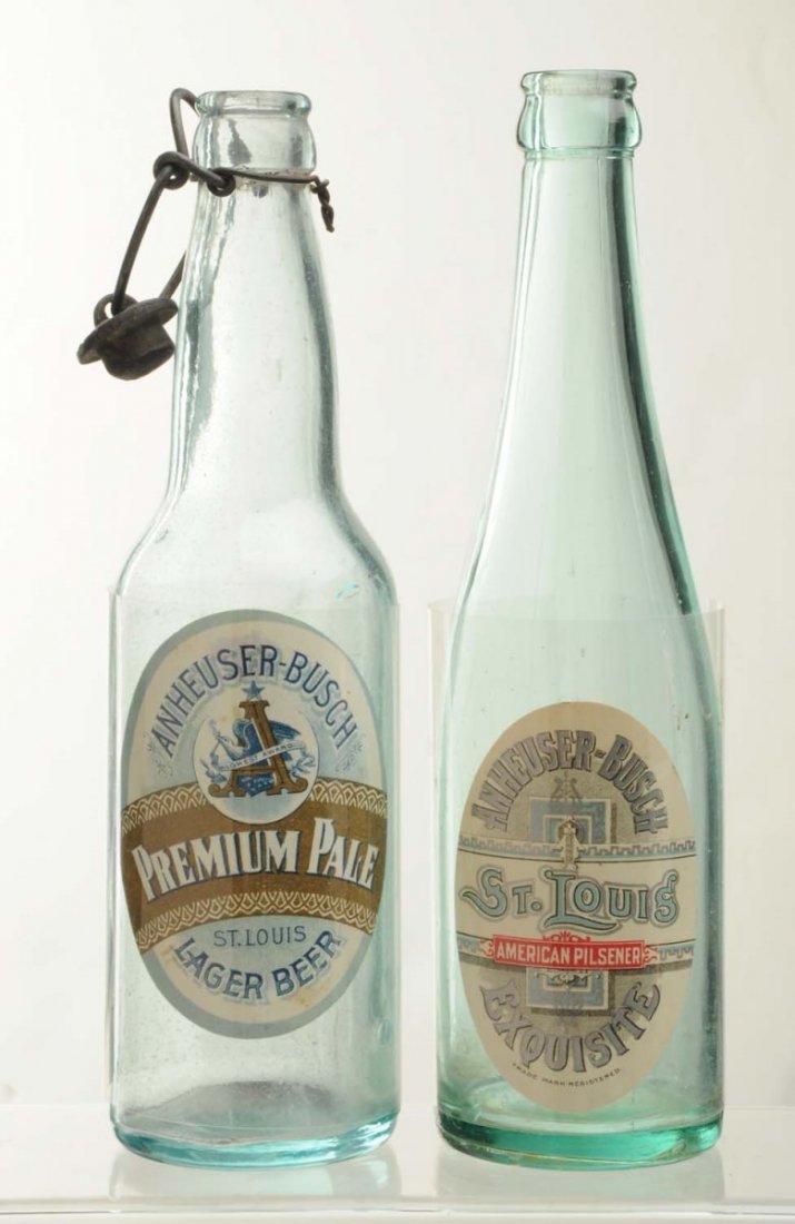 Lot Of 2: Anheuser-Busch Beer Bottles With Labels: Pre-Prohibition. This lot includes a bottle with an Anheuser-Busch St. Louis Exquisite label and a bottle with an Anheuser-Busch Premium Pale Lager Beer label. Both labels have only minor wear and may