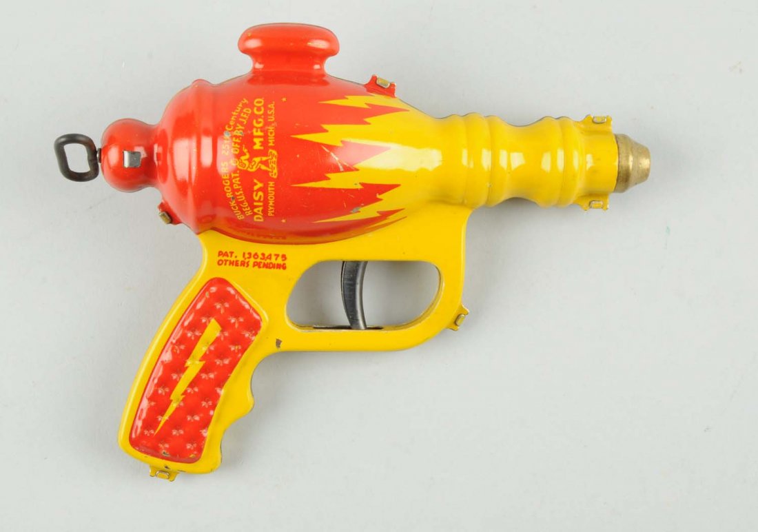 Daisy Buck Rogers Liquid Helium Water Pistol.: Tin litho water pistol with bright yellow and red coloring. Marked "Daisy Mfg. Co." and shows a small pictures of Buck Rogers on side of gun. Very difficult to find in nice condition. Condition (Excel