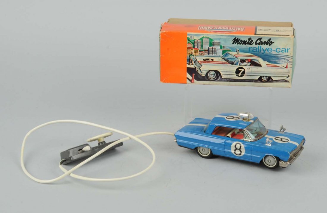 Jap. Battery-Operated Remote Control Rally-Car.: Includes original box with colorful graphics on front. Very unusual car made of tin with plastic mirrors and plastic remote. You drive it wheel. Some creasing to box. Toy has moderate scratching and w