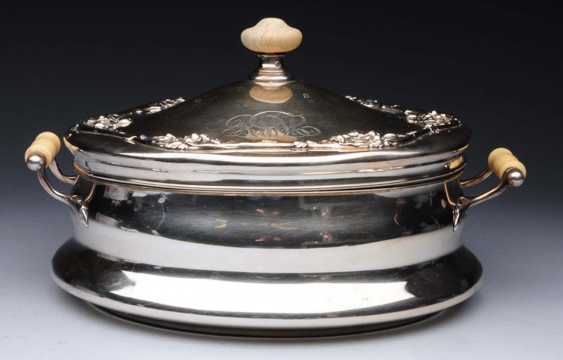 American Sterling Covered Casserole Dish.: circular with molded sides, a domed lid and applied floral decoration, and with ivory handle and finial; the interior with a ceramic liner. Length: 10-3/4 in across handles - signs of use and wear - m