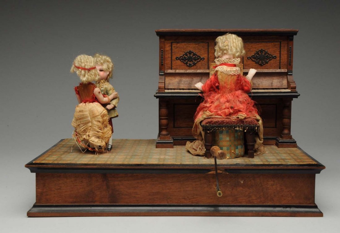Musical Toy.: Mother’s hands go up down as she plays the piano and two all-bisque children dance around. Music box plays a tune. Mother’s and girl’s silk dresses are disintegrating. Very nice one in working o