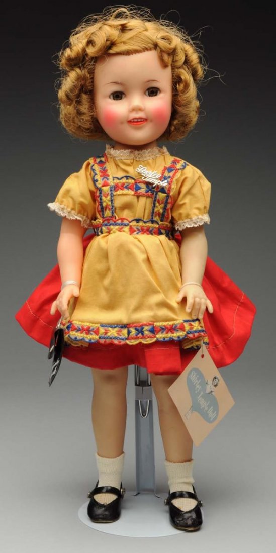 Colorful Ideal Vinyl “Shirley Temple” Doll.: 1950's all vinyl (light gray spot on forehead) with perfect original hair, lashed sleeping eyes; original tagged dress, undies, shoes and socks, script pin, wrist tag and black plastic “Shirley Temp