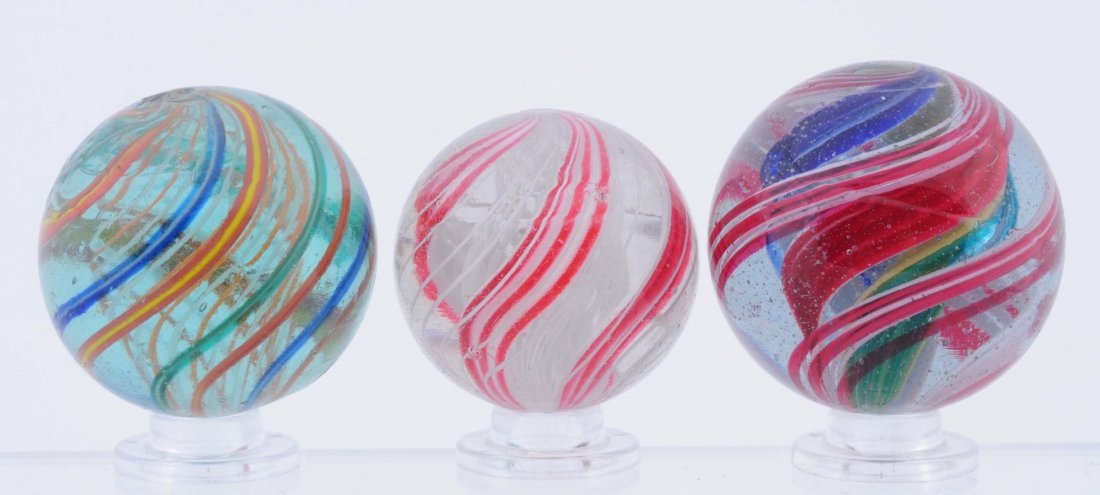 Lot Of 3: Swirl Marbles.: The smallest is a faceted pontil three stage white latticino core surrounded by red combined with white bands. Outer decoration is birdcage white latticino. The second marble is an alternating orange 