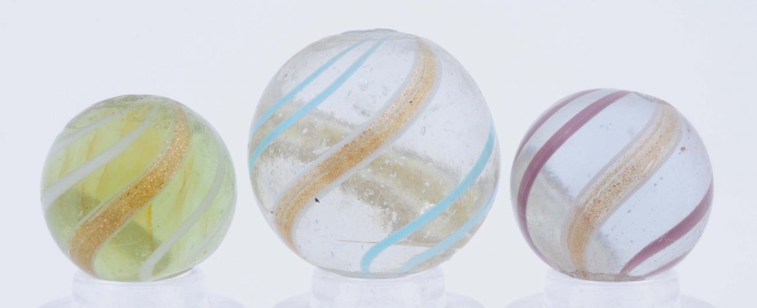 Lot Of 3: Banded Lutz Marbles.: The smallest is a light yellow base with white band, the second is a clear base with lavender bands, and the largest is clear base with baby blue bands. Condition (9.5). Size 21/32" to 27/32" Dia.