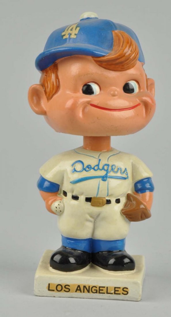 L.A Dodgers Square White Base Bobbin Head.: Circa 1961 - 1963. Made in Japan. Composition. Variation with "Dodgers" embossed on chest. Los Angeles decal on hat and base, marked "Japan" on bottom. Bright and glossy. Some minor damage under neck,
