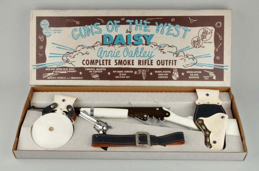 Very Scarce Daisy Annie Oakley Rifle Outfit.: Includes original box which says "Guns of the West, by Daisy. Annie Oakley Complete Smoke Rifle Outfit". Includes box insert. Looks like old store stock. Has a canteen, a belt, a rifle, a pistol, and