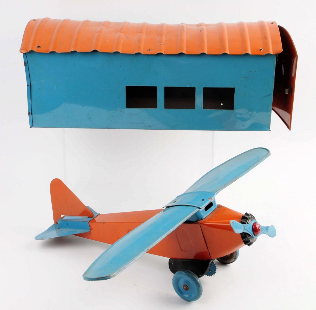 Pressed Steel American Made Airplane Hanger.: Unmarked, but probably Turner. When one plane is pushed or pulled it makes clacking noise. Single engine, folding wings, original door on hanger. Nice orange and light blue colors. Some scratching and