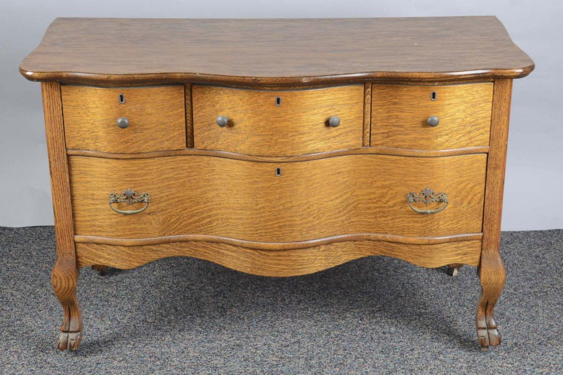 Oak Dresser Table With 4 Drawers: This chest of drawers has 4 legs with carved claw feet on wheels and a wavy curved front design. Includes knobs and ornate pulls. Condition (Very Good). Size 45" x 22" x 29"