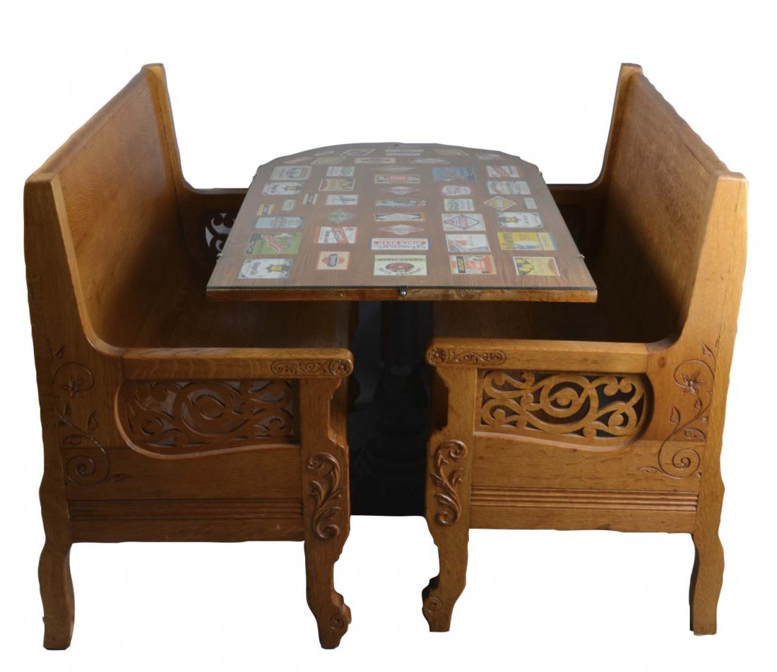 Three Piece Soda Fountain Booth And Bench Set: This lot includes 2 - oak booth style benches with intricate floral engraving and cutout arm rests and 1 - glass top wood table on a fancy cast iron base. Table is rounded on one end and top features