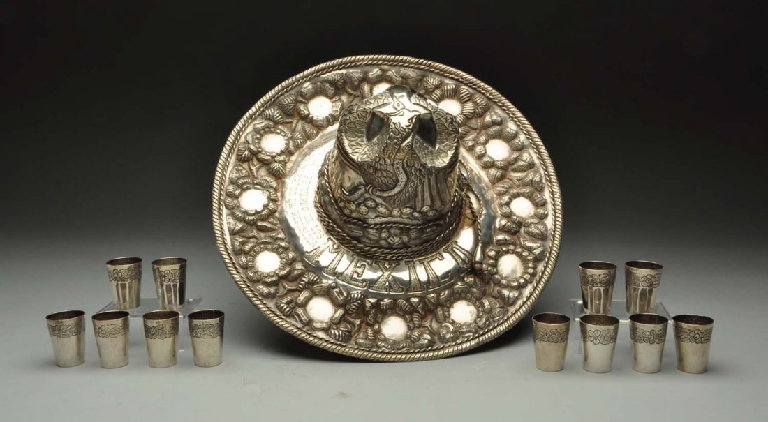 A Sterling Mexican Hat: , chased with flower heads and with cast applied ropework edges, engraved with an inscription in Spanish; and with a set of 12 shot glasses with a band of floral chasing. Circa 1943, big 14" intricate