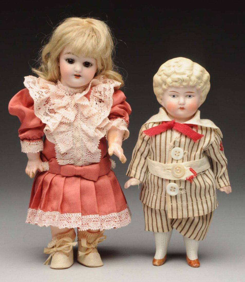 Lot Of 2: German Bisque Dolls.: All-bisque boy with molded blonde hair, painted features, jointed shoulders and hips with molded shoes and stockings, original cotton striped suit. Along with a bisque socket head Simon & Halbig 1079