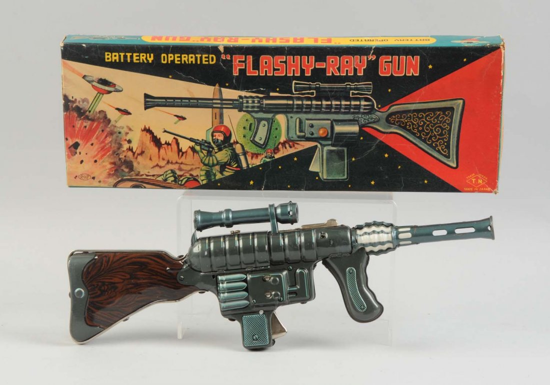 Japanese Tin Litho Flashy-Ray Gun In Box.: Battery operated. Includes original box with beautiful color graphics. Box does have cardboard insert. Box does have some creasing. Box marked T.N. Japan. Gun is all tin litho. Condition (Very Good-Ex