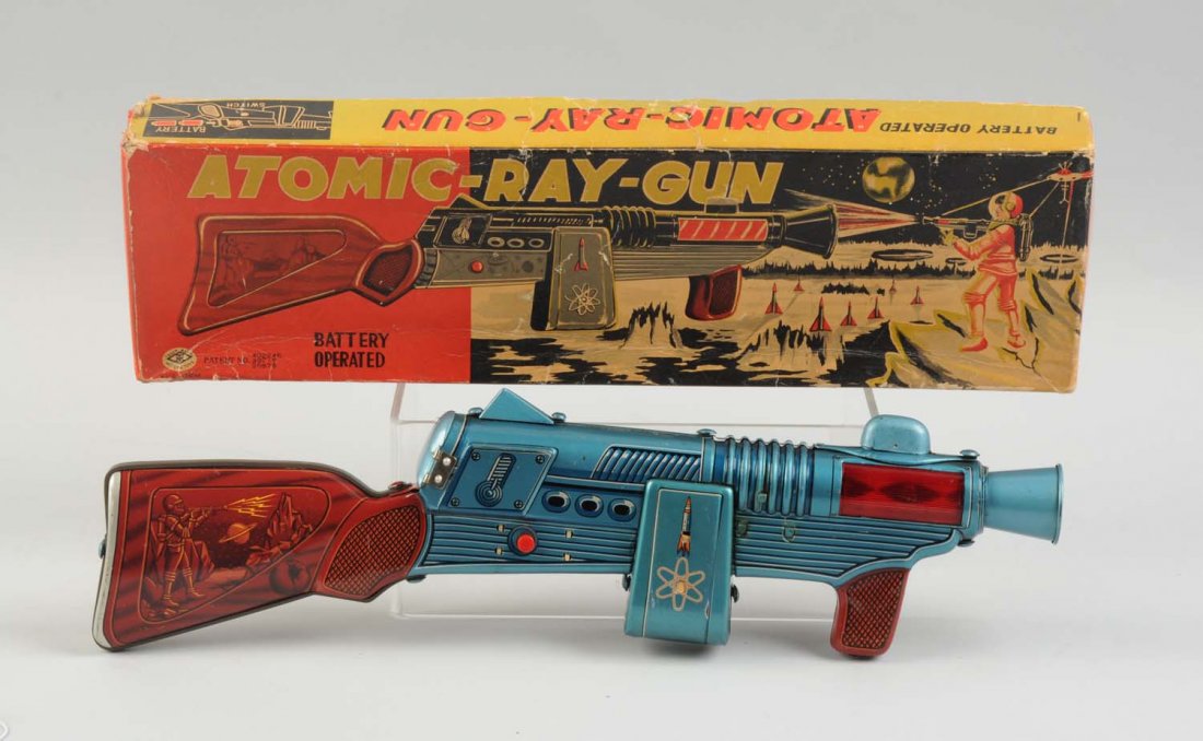 Japanese Tin Litho Atomic Ray-Gun In Box: Original box with nice color graphics on front of box. Made by Modern Toys, Japan. All tin litho. Nice graphic space scenes on both sides of rifle butt. Some creasing and wear to box. Very little wear