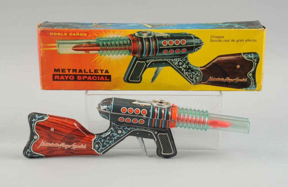 Spanish Tin Litho Friction Space Rifle In Box.: Colorful original box showing the depiction of gun on lid and space scenes on side aprons. Gun is mostly tin litho with plastic barrels. Marked "Rayo Spacial" Minor creasing to box. Little wear to gun