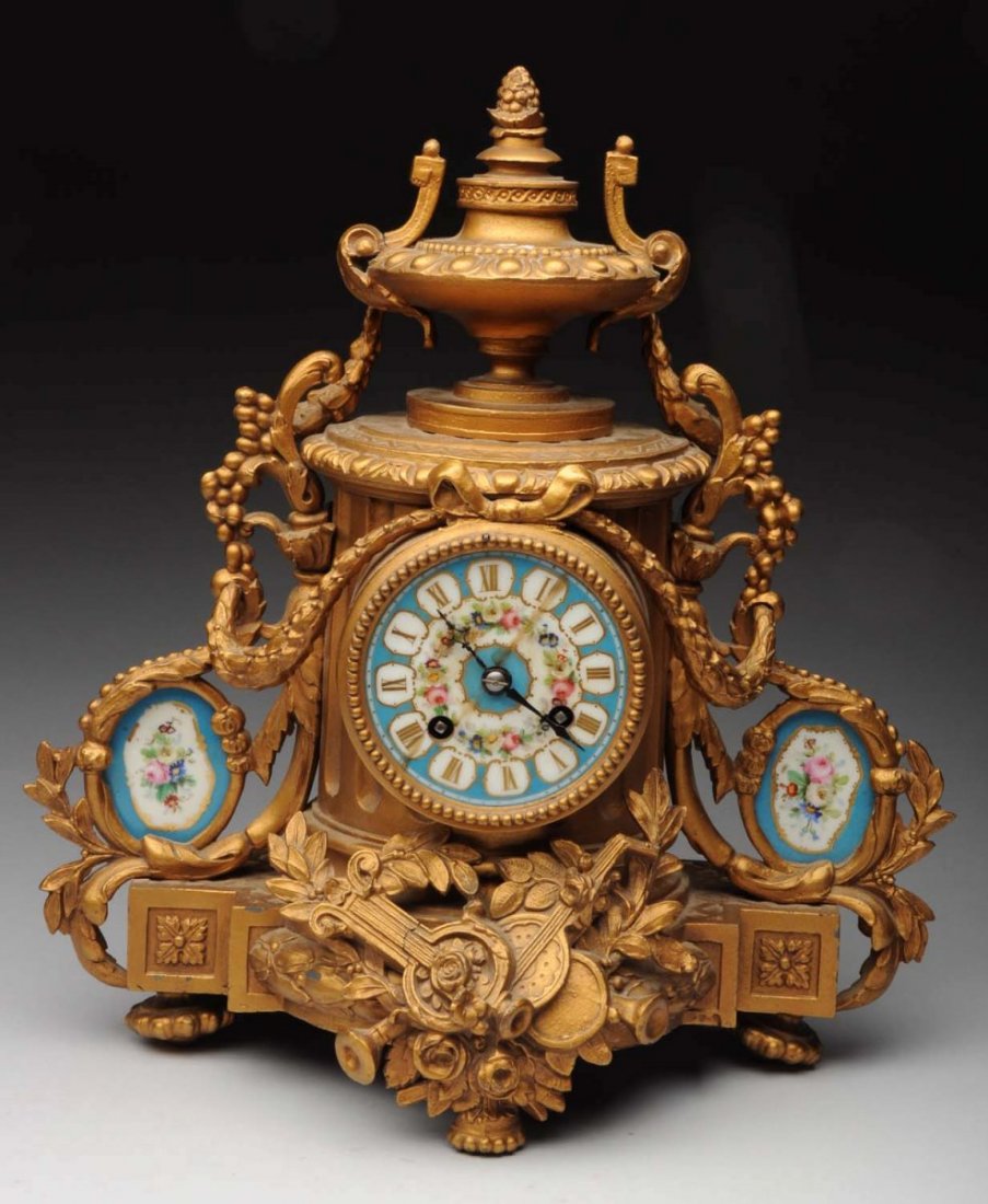 Bronze and Enamel Clock.: Porcelain face with an old repair. Two enamel discs on the sides. Time and strike works, no key. Size 13 - 1/2" T.