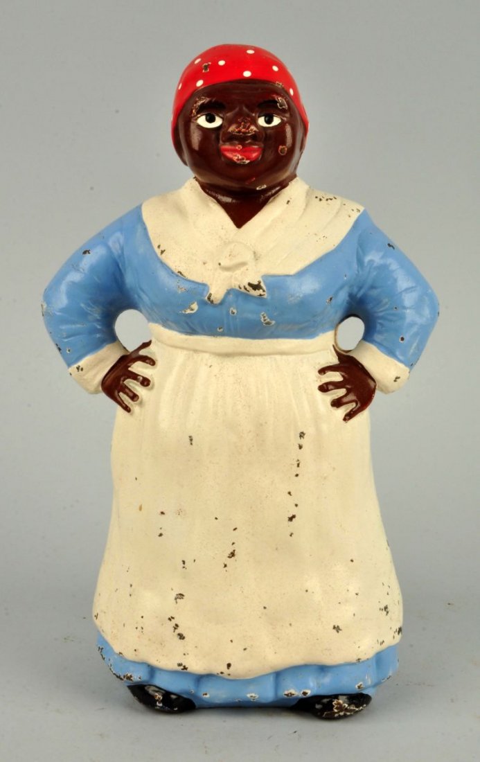 Cast Iron Southern Mammy w/ Hands on Hips Doorstop: Hubley. Depicts full-figure mammy with hands on hips, wearing traditional apron and scarf. Blue dress paint variation. Condition (Excellent Plus). Size 12'' T.