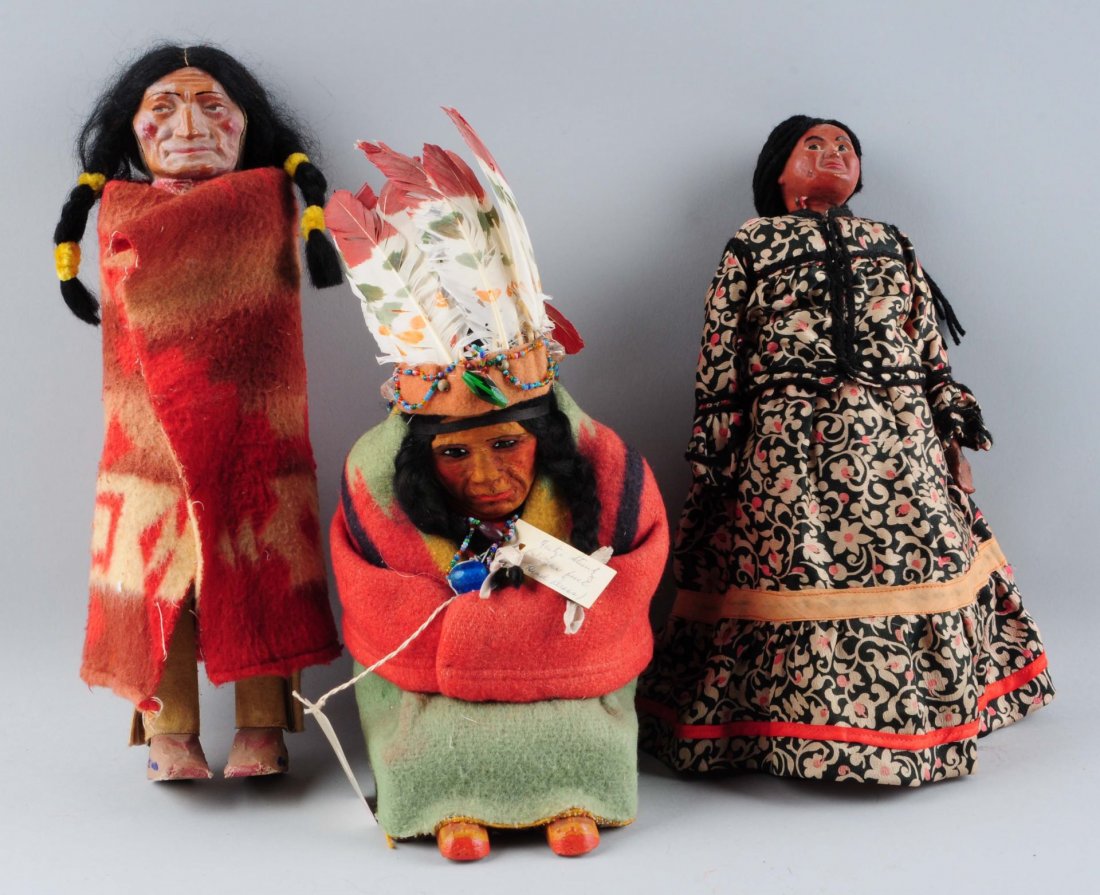 Lot Of 3: Vintage Native American Dolls.: One Skookum, a carved wooden sitting Indian Chief with headdress and a papier mache squaw. Condition (Good). Size Largest: 13-1/2'' T.