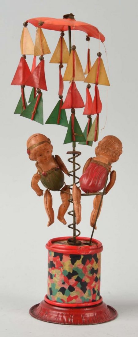 Unusual Pre-War Japanese Celluloid Whirligig Toy.: Depicts two girls going up and down spinning pole while umbrella spins on top. All original. Some pieces of umbrella are detached but present. Unusual mechanism with nice action. Some slight denting t