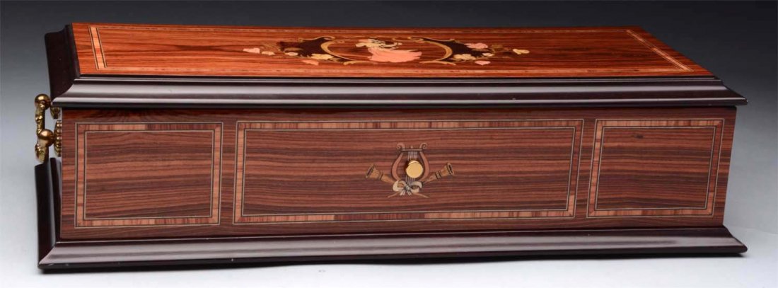 Reuge Interchangeable Cylinder Music Box.: Burled walnut case. Sixty-four teeth. The box contains five cylinders. The tune sheet is present and is in operating condition at the time of inspection. Condition (Excellent). Size 15-1/4'' x 6-1/2''