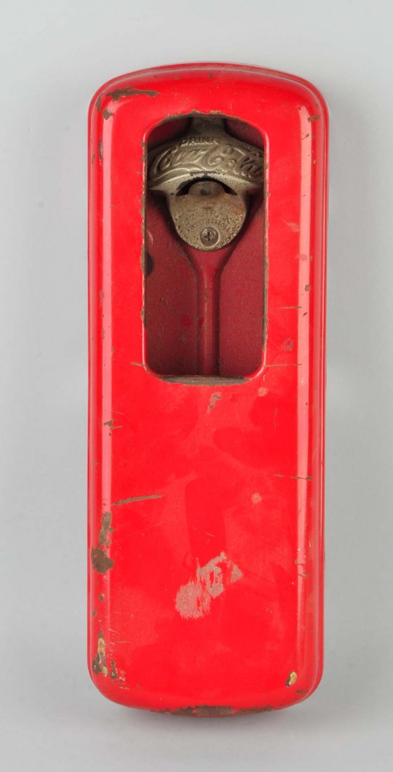 Red Coca-Cola Porcelain Bottle Opener.: A red rectangular porcelain bottle opener. The bottle opener has “Drink Coca-Cola” on the metal. Heavily rusted with scratches and paint deficient areas.