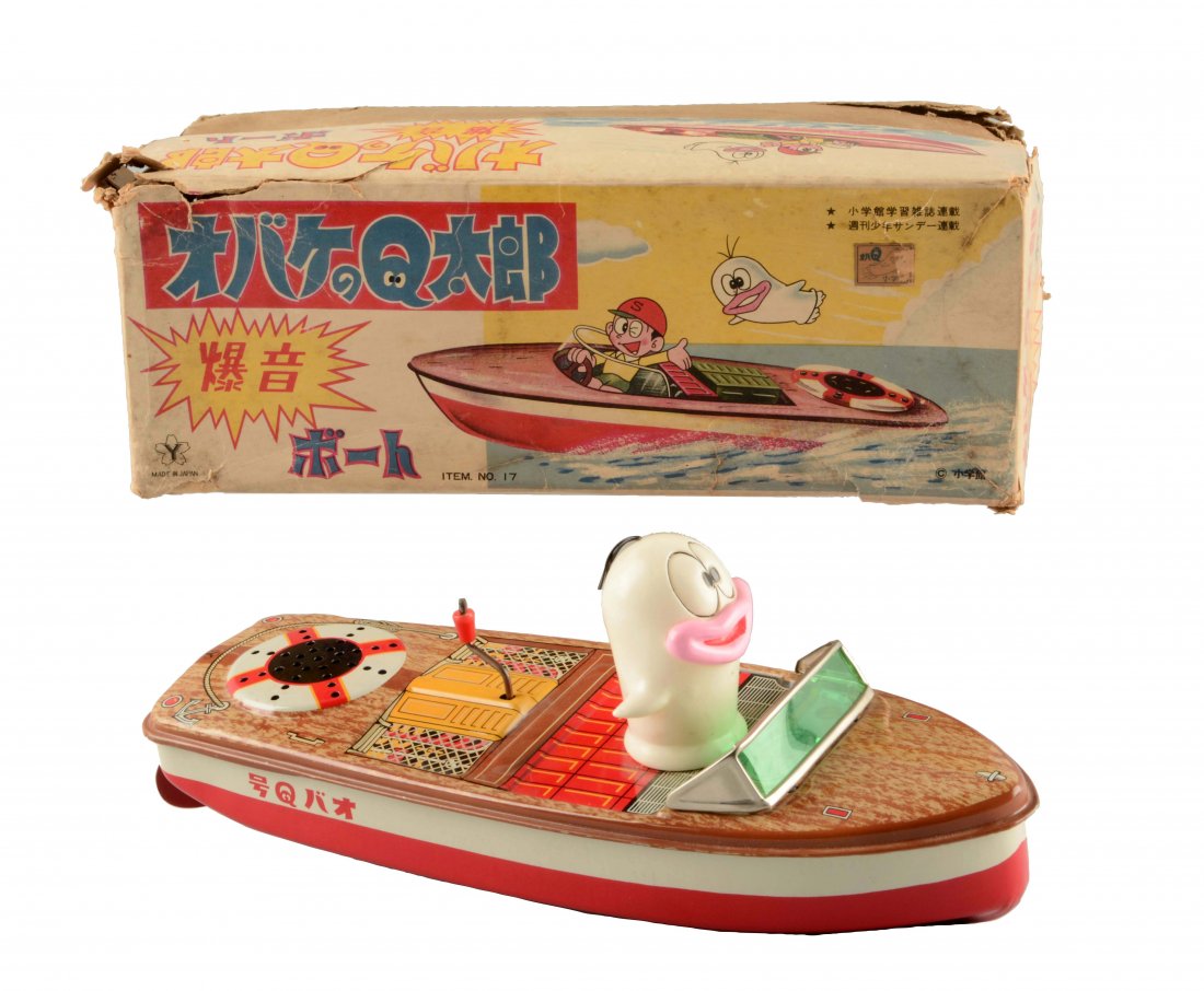 Japanese Tin Litho Friction Oba-Q Taro Tin Boat: Made by Yonezawa. Includes scarce original box with some staining, tearing and creasing but still displays well. When cranked, boat makes engine noise. Boat is tin litho and the whimsical ghost that i