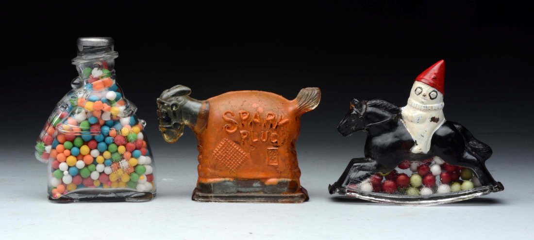 Lot Of 3: Glass Figure Candy Containers.: Clown on rocking horse. Original closure, contents not original. 95% paint. Barney google bottle. Replaced metal cap and contents not original. Spark plug. 98% paint. Original closure. (Very Good - Ex