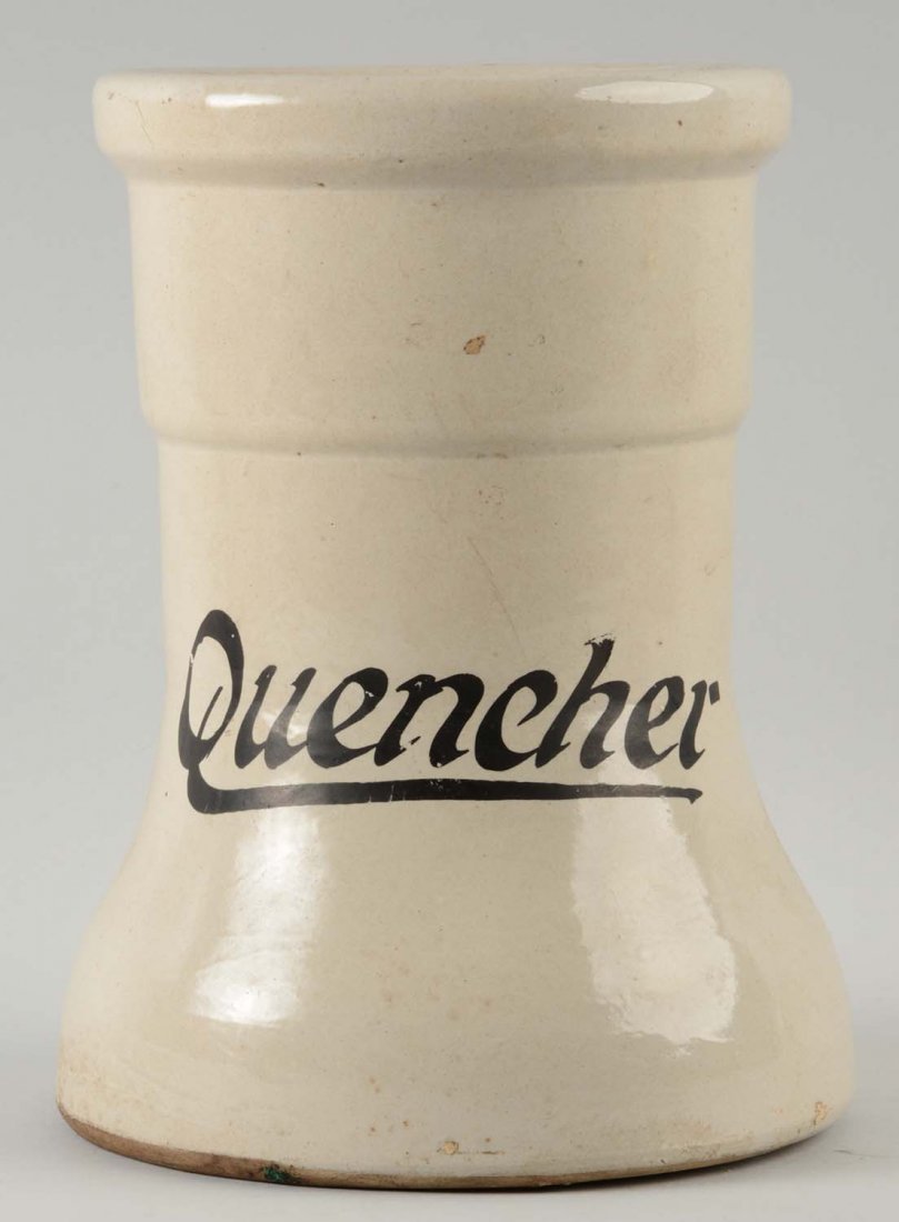 Quencher Syrup Dispenser Base: This lot is of a Quencher syrup dispenser base. The body of the base is an off white color, with "Quencher" on black lettering. The dispenser is found on one side. Minor nicks and scratches are presen