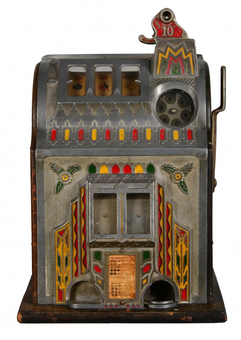 **10¢ Pace "Fancy Front" Comet Slot Machine: Escalator bell slot machine produced by Pace Manufacturing Co.. This model features a "Fancy Front" design. Missing back panel. Shows wear overall including a hole in the top casting. Includes one key