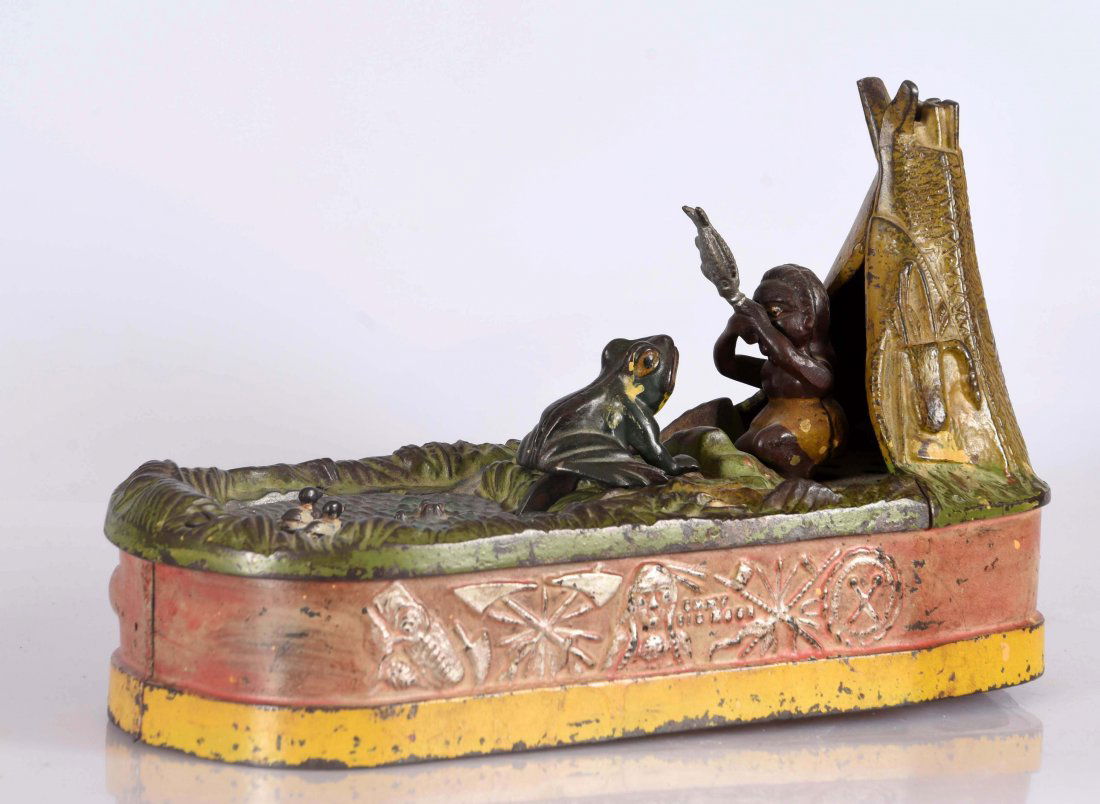 J. & E. Stevens Chief Big Moon Cast Iron Mechanical: Place a coin in the slot in front of the pond and press the lever. As the coin disappears, the frog springs from the pond after the fish. The Indian squaw lifts the fish away from the frog and the coi