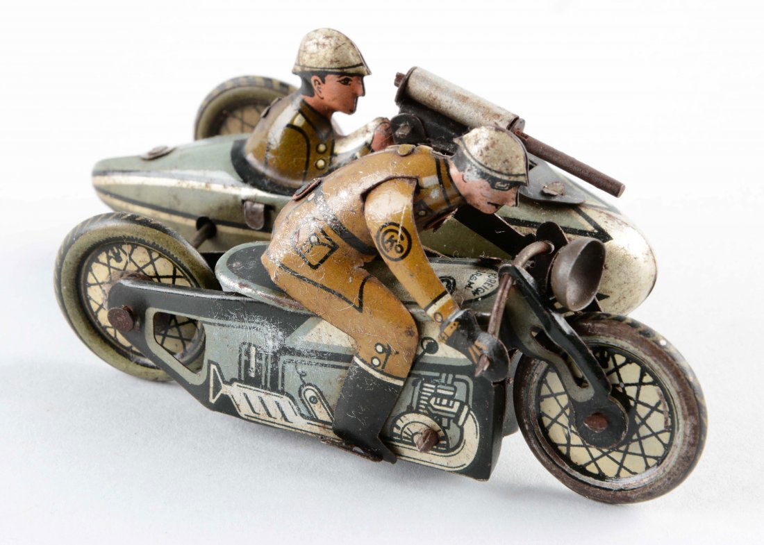 German CKO Tin Litho Wind Up Motorcyclist w/ Side Car.: Small size variation. Military version. Marked "CKO" on right shoulder of driver. Marked "Foreign DRGM" on top of gas tank. Original headlight. Side car passenger shooting machine gun. Needs flint to