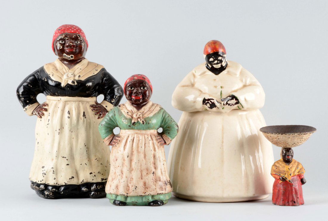 Lot Of 4: Black Americana Figures.: Lot includes: Cast iron mammy with bowl on her head, 5" tall. McCoy Cookie Jar with paint loss to face and hands. Cast iron door stop with green dress, 9" tall. Cast iron door stop with blue dress, 12