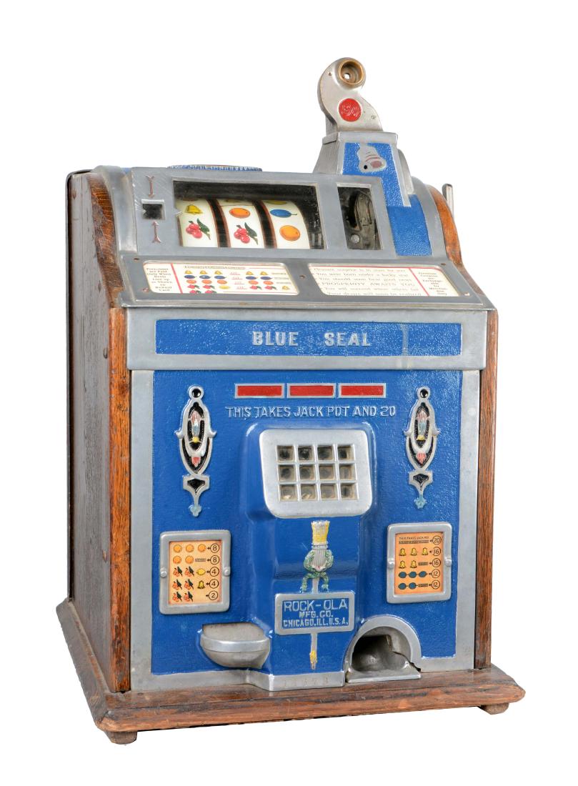 **5¢ Rock-Ola/Watling "Blue Seal" Slot Machine: This Watling machine was manufactured in 1920 and has a cast aluminum Rock-Ola front with Serial No. 14673. The wood cabinet has Serial No. 29919. Two keys are included, but one is nearly broken. (Ver