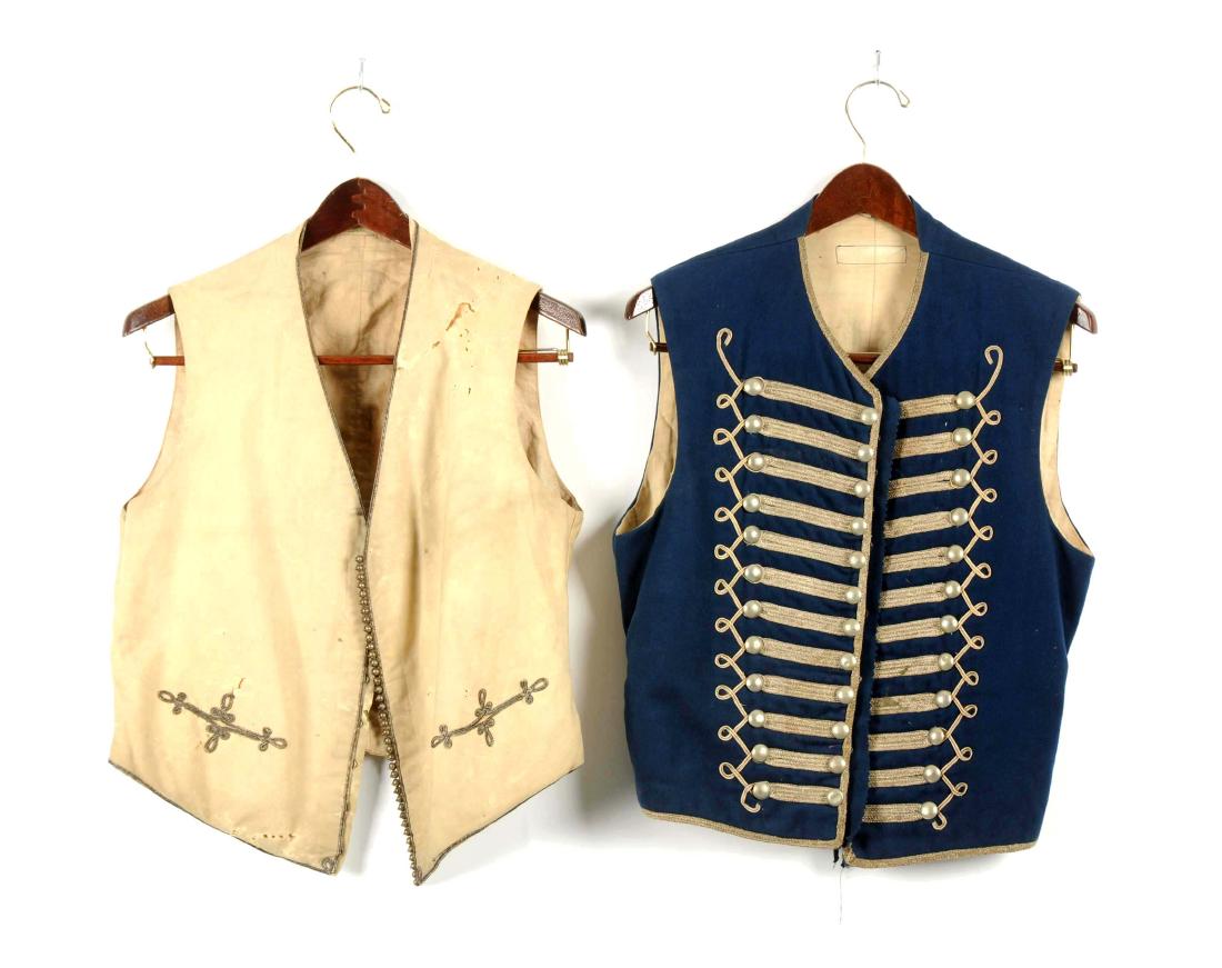 Lot of 2: Officer’s Waistcoats.: Comprised of: 1) British white superfine mess vest with silver Prussian binding edging and ball buttons closing by hooks and eyes. Soiling and moth damage. 2) European, Hussar Style, officer’s mediu