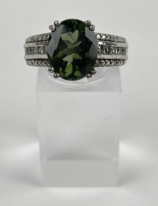 5.301 Gram Sterling Silver Ring with Oval Green Gemstone: Size 7 925 Sterling silver ring featuring an oval green gemstone centerpiece and pave-set clear stones along the band. Prong setting secures the central green stone, providing durability and style. Ge