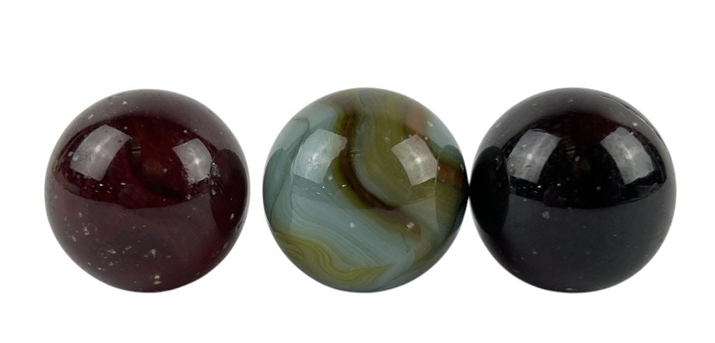 (3) Glass Glowing Shooter Marbles: (3) Glass Glowing Shooter Marbles each featuring a unique set of swirls in colors such as blue, brown, yellow, and orange. Each marble has swirls that glow under blacklight. Each marble is about 1 inc